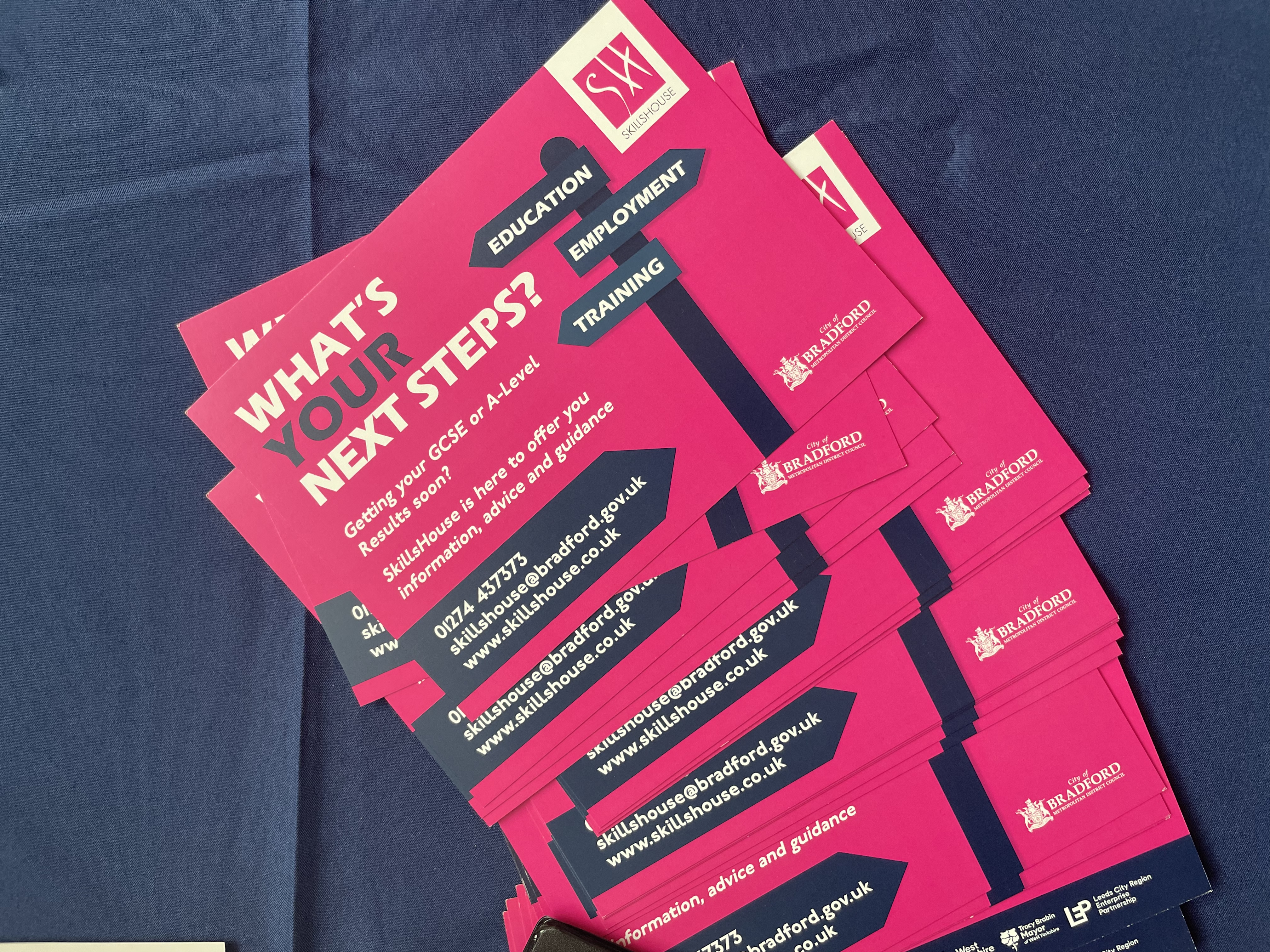 A stack of bright pink and blue leaflets advertising the Next Steps careers event