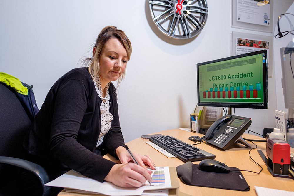 A woman working at a desk with computer and telephone