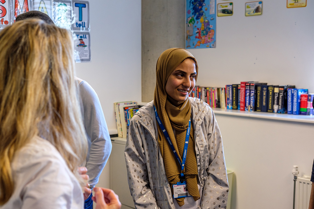 Woman wearing an ID badge, shelf of books in the background