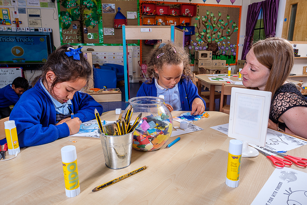 Two young girls wearing school uniform talking to a woman sat next to them