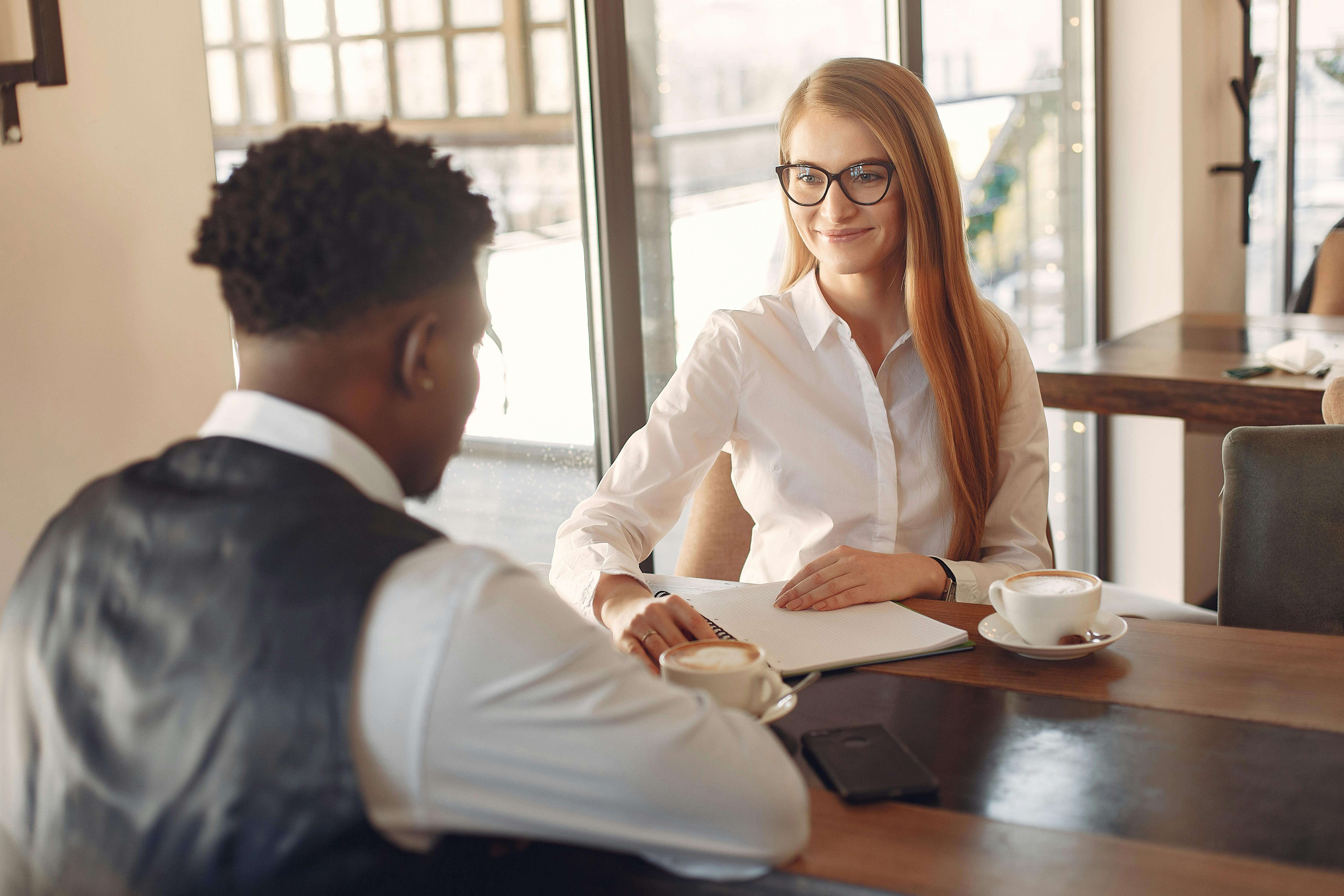 A smiling woman and man sat at a table drinking coffee