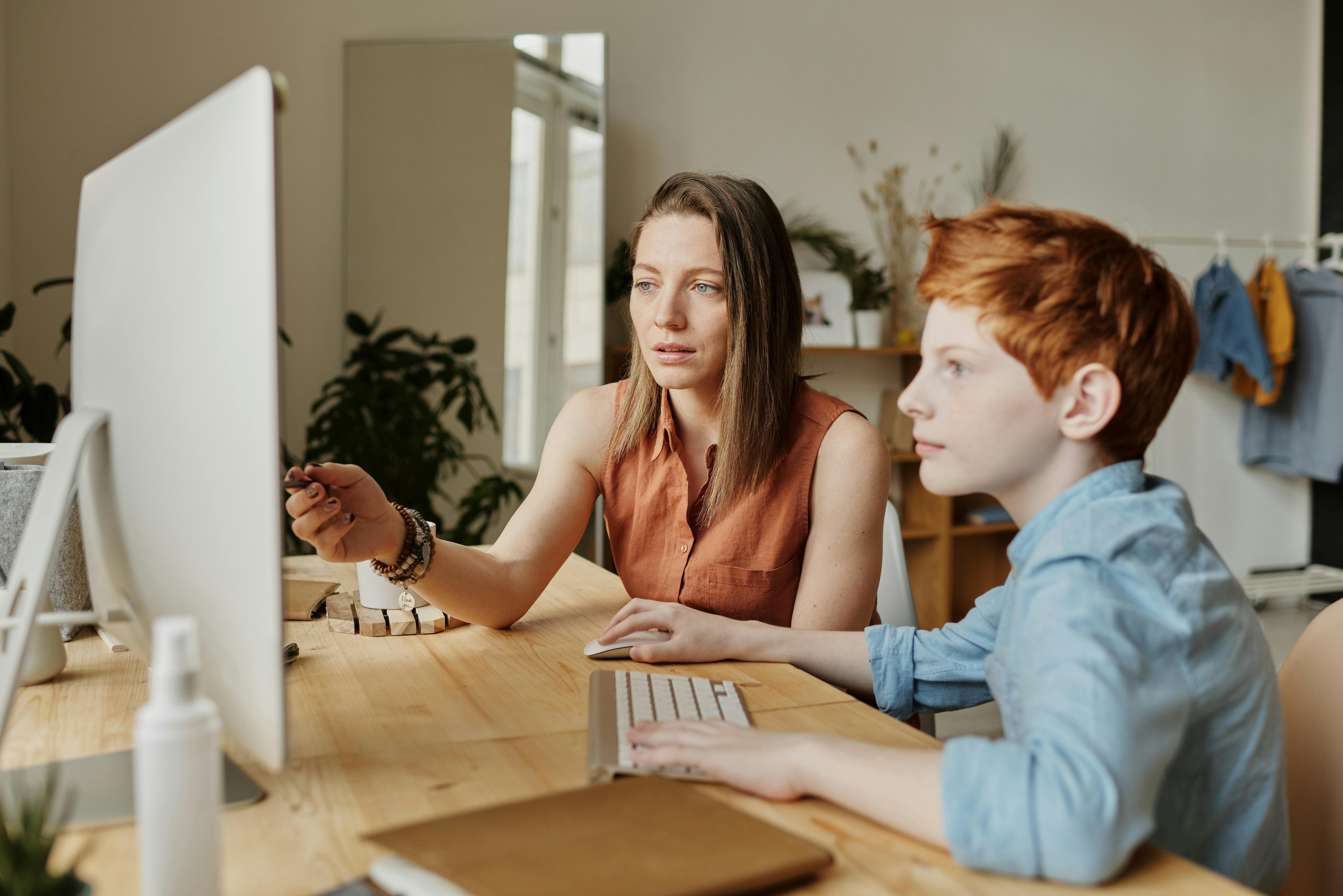A woman showing a young boy something on a computer